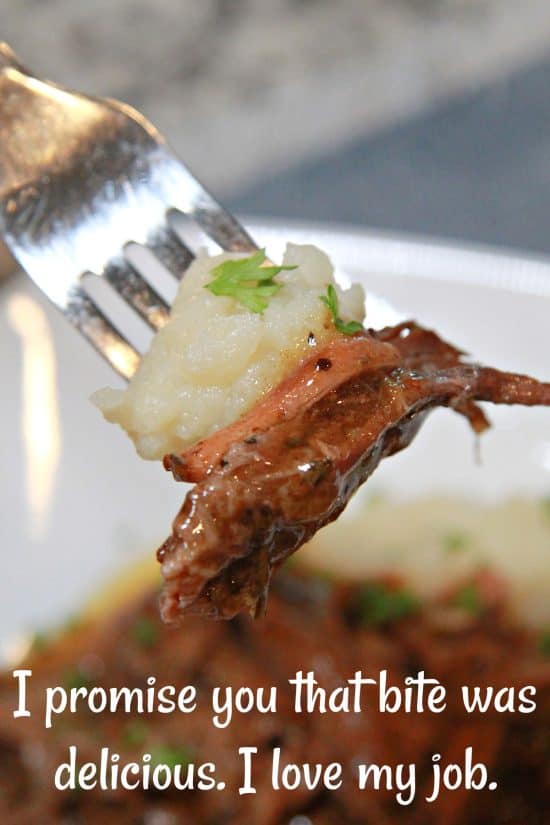 A bite of mashed potatoes with shredded Chuck roast slowly cooked in a gravy.
