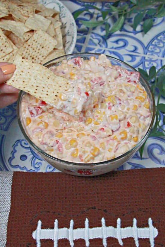 A delicious appetizer made with white and yellow corn kernels, cream cheese, sour cream, diced tomatoes, cheddar cheese, and some tasty seasonings.